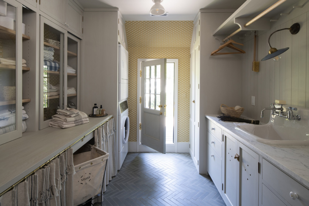 Idee per una sala lavanderia con lavello da incasso, lavatrice e asciugatrice a colonna e pavimento grigio