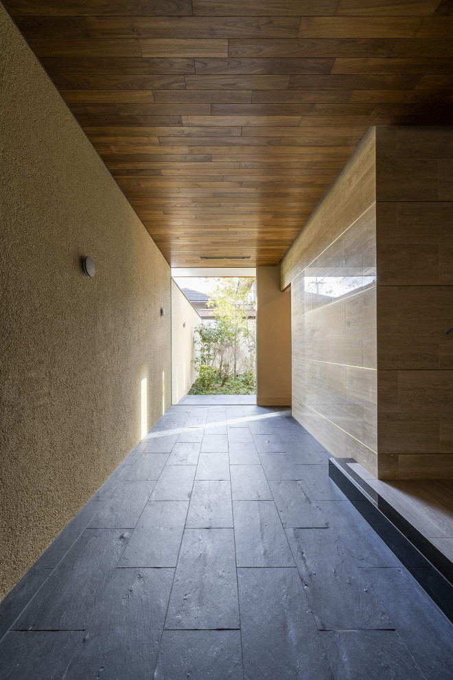 Idee per un ampio ingresso con pareti beige, pavimento in granito, una porta singola, una porta in legno scuro, pavimento nero, soffitto in legno e pareti in mattoni