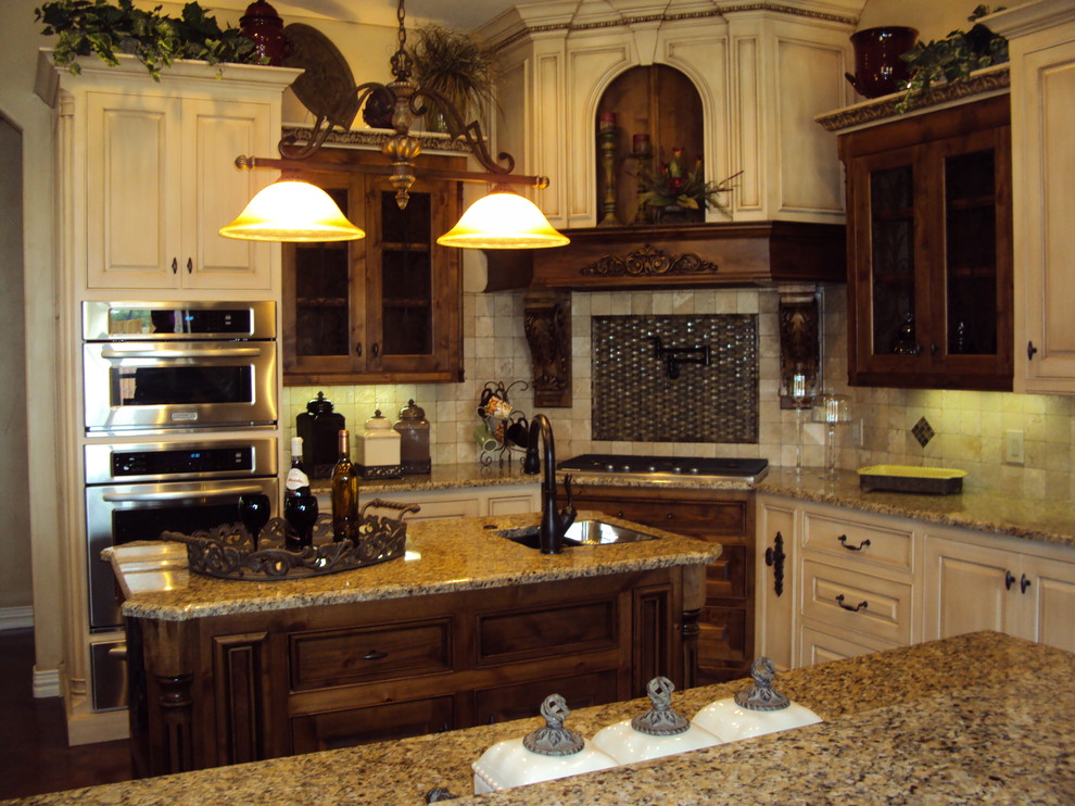 This is an example of a large arts and crafts u-shaped separate kitchen in Dallas with a double-bowl sink, raised-panel cabinets, beige cabinets, granite benchtops, beige splashback, ceramic splashback, stainless steel appliances, with island, dark hardwood floors and brown floor.