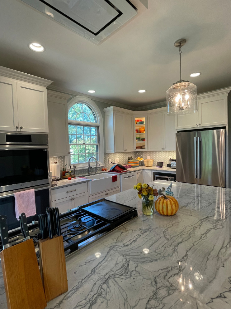 Example of a large transitional light wood floor and brown floor eat-in kitchen design with an undermount sink, shaker cabinets, white cabinets, quartzite countertops, green backsplash, marble backsplash, stainless steel appliances, an island and gray countertops