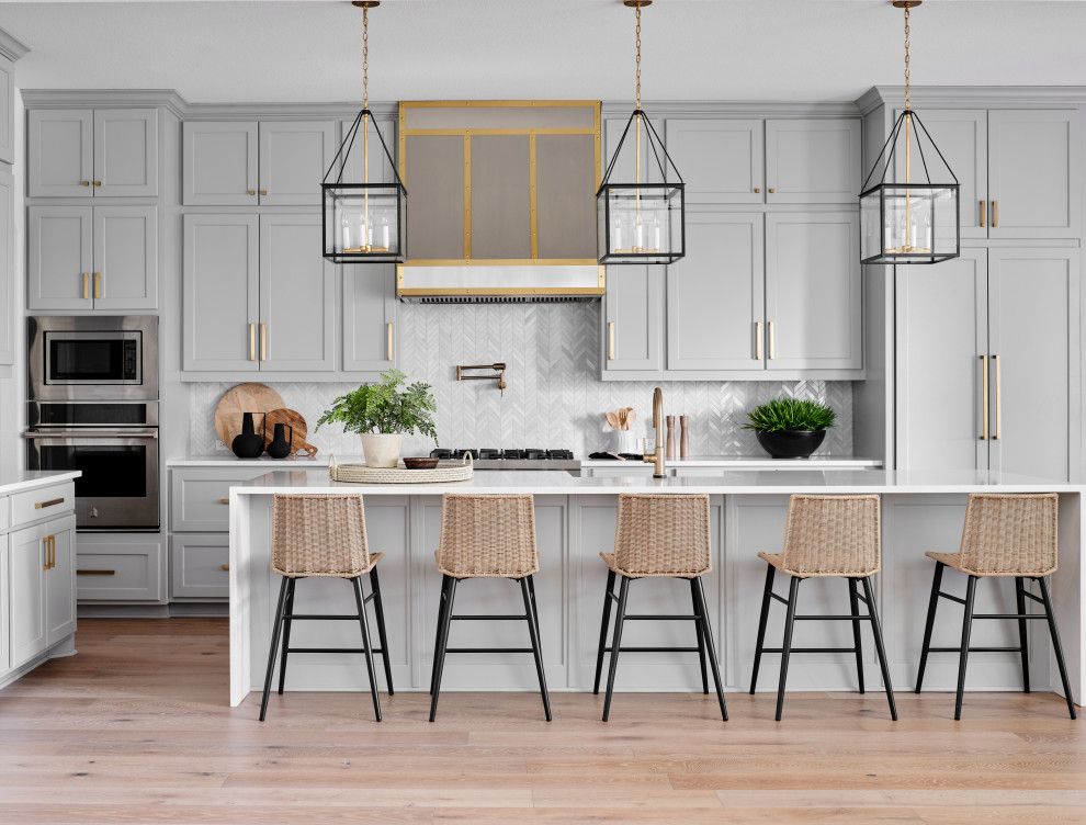 Belterra Project- Furnishings, Lighting Fixtures & Interior Design - This black, gray and gold urban farmhouse kitchen is the hub of the home for this busy family.  Our team changed out the existing plain kitchen hood for this showstopper custom stainless hood with gold strapping and rivets.  This provided a much needed focal point for this lovely kitchen.  In addition, we changed out the 36" refrigerator to a roomier 42" refrigerator and built-in a matching paneled refrigerator cabinet.  We also added the antique gold linear hardware and black and gold lighting to give it a streamlined look.  Touches of black tie the kitchen design into the rest of the home's mostly black and white color scheme.  The woven counter stools give the space a touch of casual elegance.  A new champagne gold kitchen faucet and potfiller add additional style, while greenery and wood accessories add a touch of warmth.