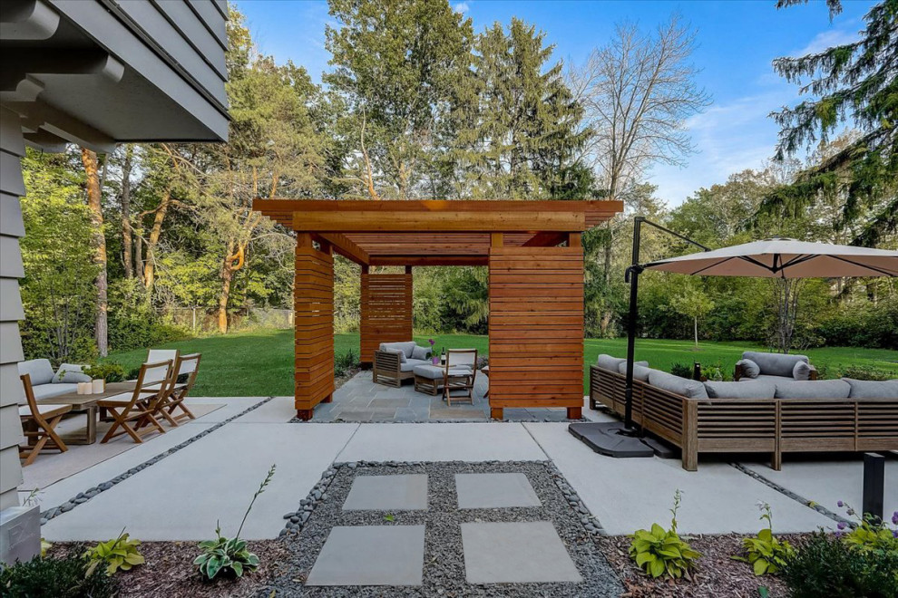 На фото: пергола во дворе частного дома среднего размера на заднем дворе в стиле модернизм с покрытием из бетонных плит