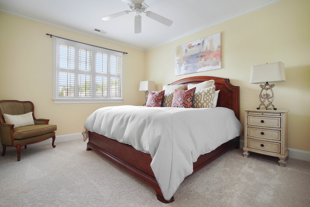 Photo of a transitional bedroom in Charlotte with yellow walls, carpet and beige floor.