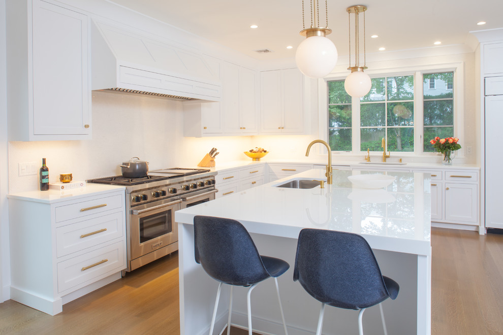 Inspiration for a large contemporary u-shaped separate kitchen in New York with an undermount sink, recessed-panel cabinets, white cabinets, glass benchtops, white splashback, mosaic tile splashback, panelled appliances, light hardwood floors and with island.
