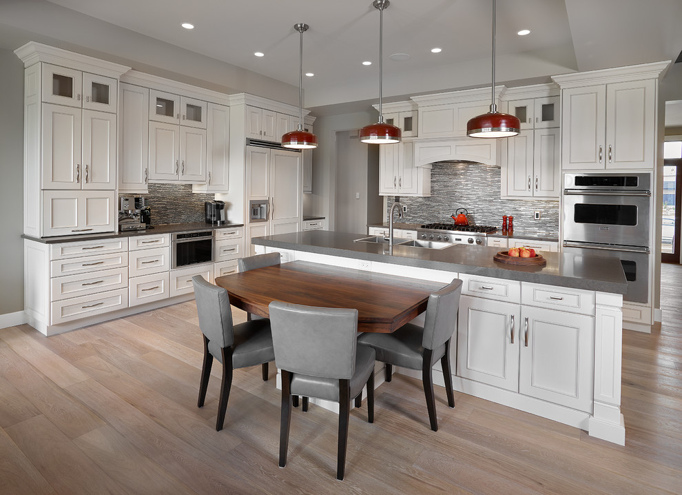 Inspiration for a large transitional l-shaped light wood floor and beige floor eat-in kitchen remodel in Edmonton with a farmhouse sink, recessed-panel cabinets, white cabinets, quartz countertops, gray backsplash, matchstick tile backsplash, stainless steel appliances and an island