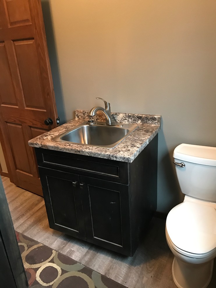This is an example of a mid-sized traditional powder room in Other with shaker cabinets, dark wood cabinets, a one-piece toilet, beige walls, light hardwood floors, an undermount sink and granite benchtops.