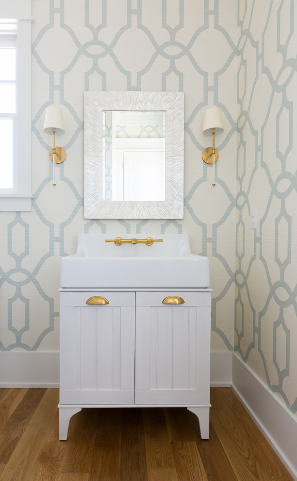 Photo of a mid-sized country powder room in Charleston with furniture-like cabinets, white cabinets, brown floor, blue walls, medium hardwood floors, an integrated sink, engineered quartz benchtops and white benchtops.