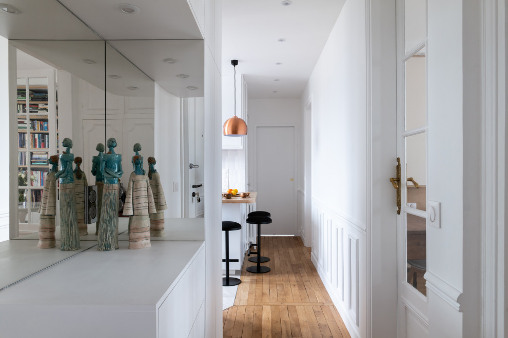 Photo of a medium sized scandi foyer in Paris with white walls, light hardwood flooring and wainscoting.