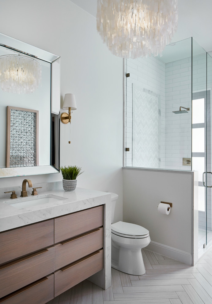 Mid-sized transitional kids bathroom in Austin with flat-panel cabinets, light wood cabinets, engineered quartz benchtops, a two-piece toilet, white tile, marble, white walls, porcelain floors, an undermount sink, beige floor, a hinged shower door and grey benchtops.