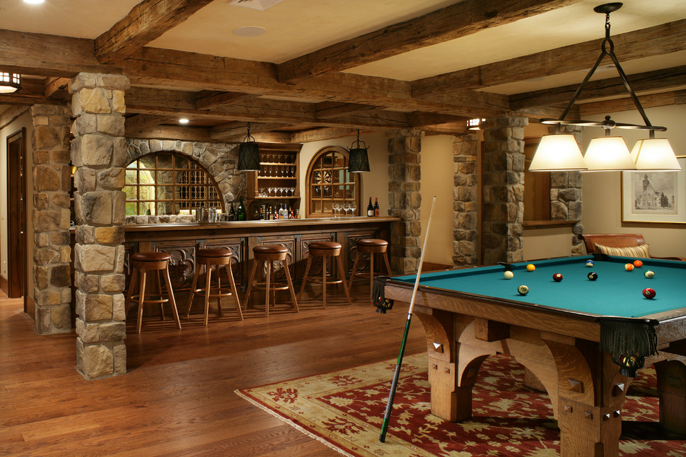 Photo of an expansive country fully buried basement in New York with beige walls, brown floor, medium hardwood floors, no fireplace and a home bar.