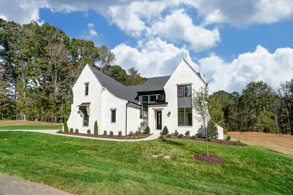 Imagen de fachada de casa blanca y negra grande de dos plantas con ladrillo pintado, tejado a dos aguas, tejado de teja de madera y panel y listón