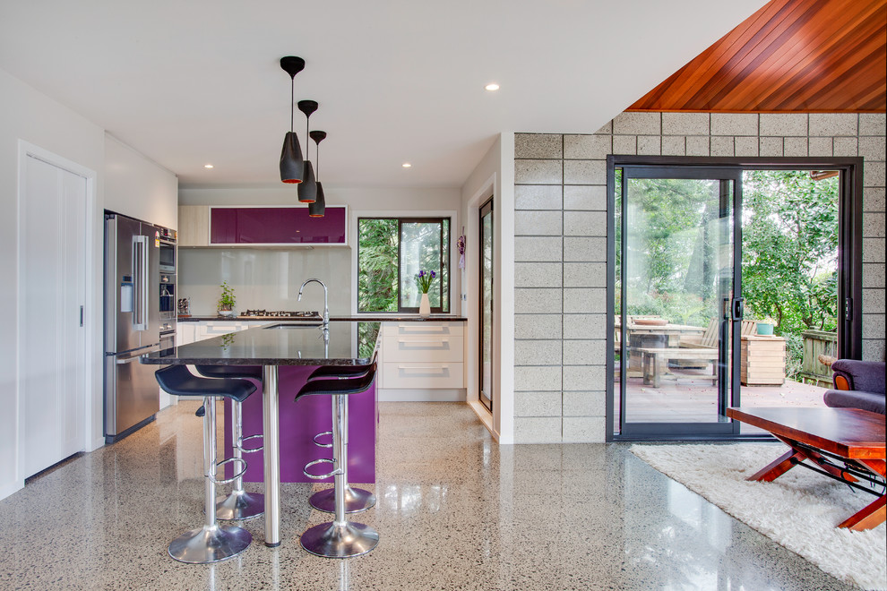 Mid-sized contemporary l-shaped eat-in kitchen in Auckland with an undermount sink, flat-panel cabinets, purple cabinets, quartz benchtops, grey splashback, glass sheet splashback, stainless steel appliances, concrete floors, with island and grey floor.