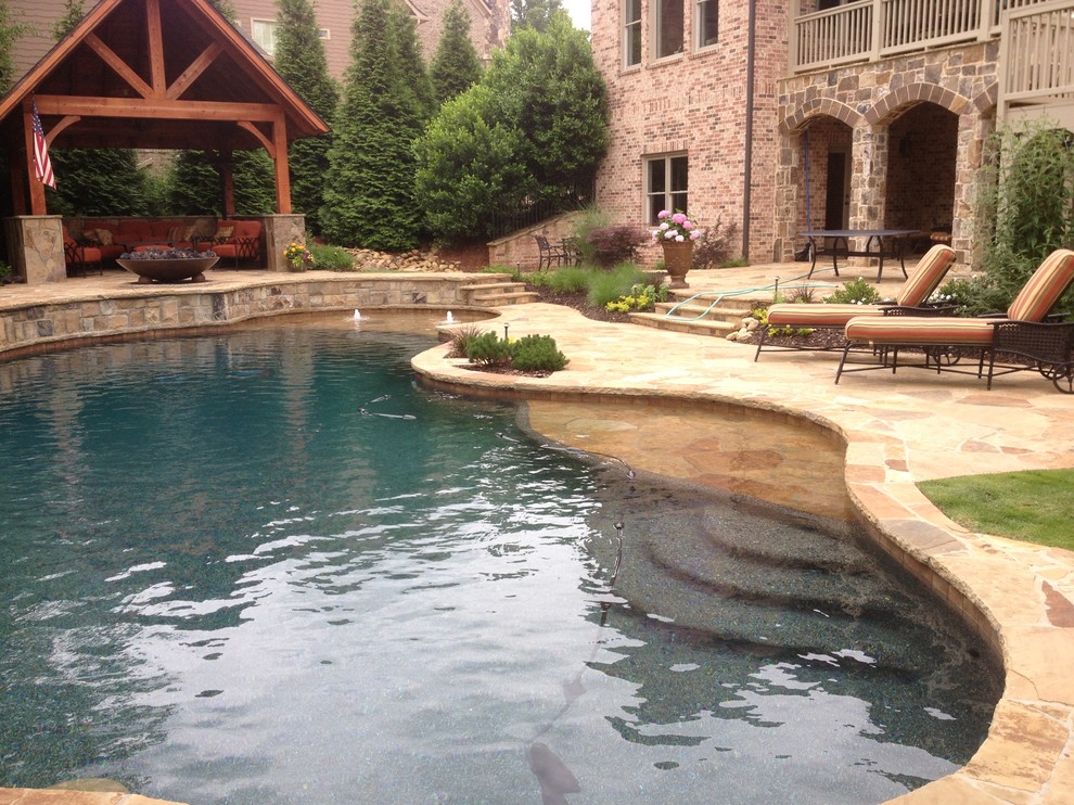 Expansive traditional backyard custom-shaped natural pool in Atlanta with a pool house and natural stone pavers.