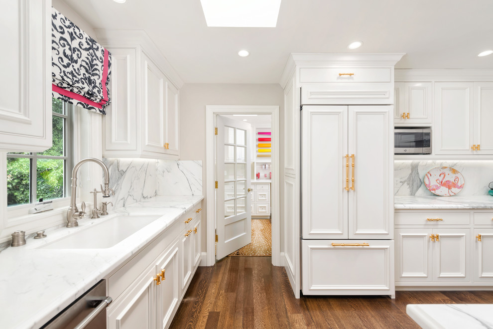 Photo of a mid-sized traditional u-shaped open plan kitchen in San Francisco with an undermount sink, recessed-panel cabinets, white cabinets, marble benchtops, yellow splashback, marble splashback, stainless steel appliances, medium hardwood floors, a peninsula, brown floor and white benchtop.