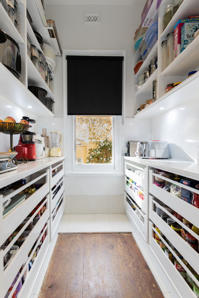 This is an example of a large contemporary l-shaped kitchen pantry in Melbourne with flat-panel cabinets, white cabinets, quartz benchtops, with island, white benchtop, an undermount sink, engineered quartz splashback, stainless steel appliances and porcelain floors.