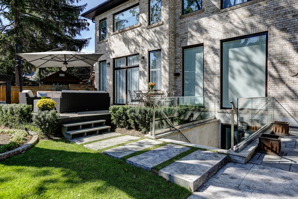 Example of a mid-sized transitional backyard stamped concrete and rectangular pool design in Toronto
