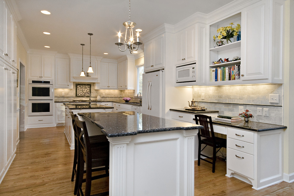 Photo of a large traditional l-shaped eat-in kitchen in Raleigh with white appliances, an undermount sink, raised-panel cabinets, white cabinets, granite benchtops, white splashback, blue benchtop, marble splashback, medium hardwood floors, multiple islands and orange floor.