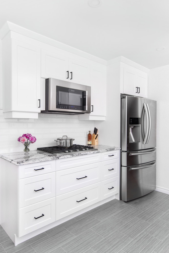 Inspiration for a mid-sized transitional galley porcelain tile and gray floor eat-in kitchen remodel with a double-bowl sink, shaker cabinets, white cabinets, granite countertops, white backsplash, subway tile backsplash, stainless steel appliances, no island and gray countertops
