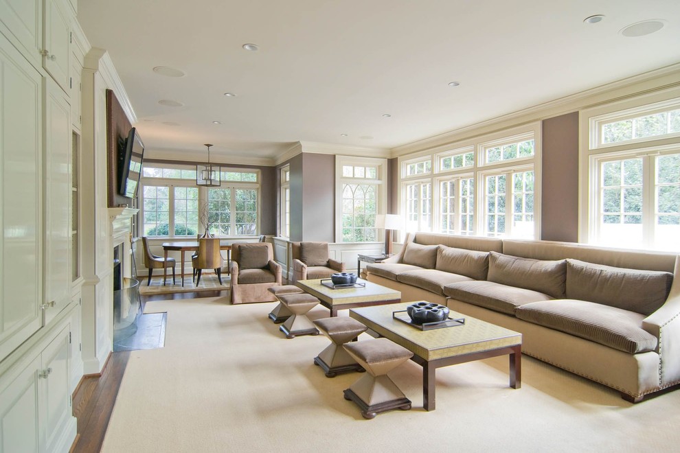 This is an example of a mid-sized transitional enclosed family room in Charlotte with beige walls, carpet, a standard fireplace, a wood fireplace surround, a wall-mounted tv and beige floor.
