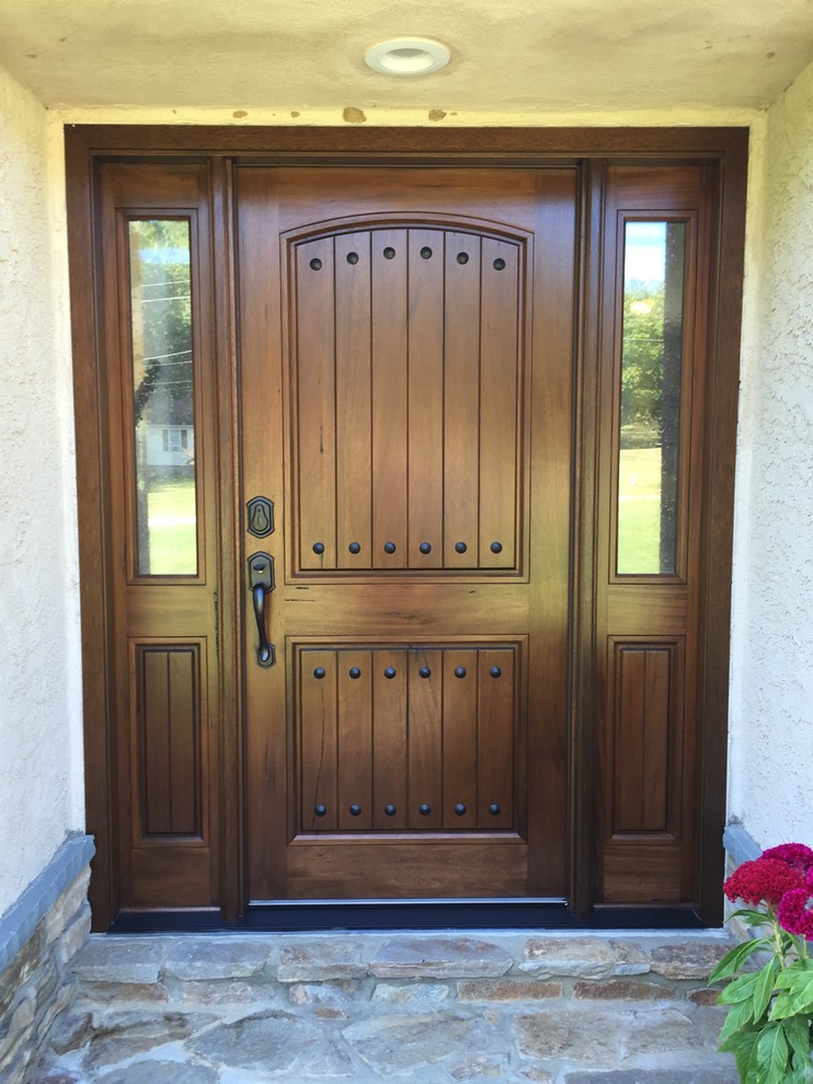 This is an example of a mid-sized country front door in Philadelphia with a single front door and a dark wood front door.
