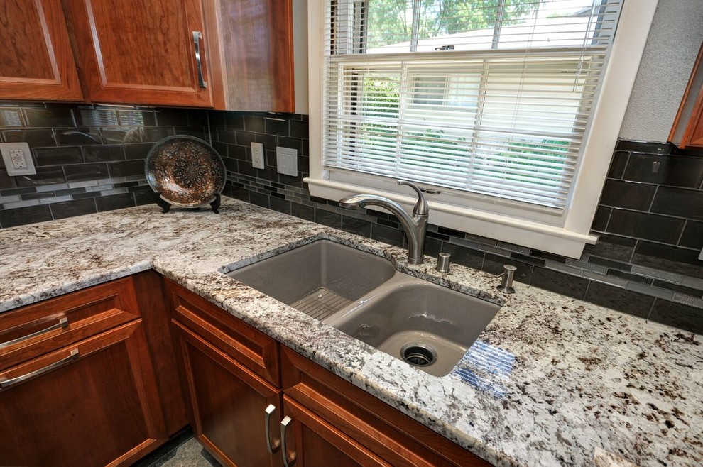 Enclosed kitchen - mid-sized transitional l-shaped vinyl floor enclosed kitchen idea in Milwaukee with an undermount sink, raised-panel cabinets, medium tone wood cabinets, granite countertops, gray backsplash, glass tile backsplash and stainless steel appliances