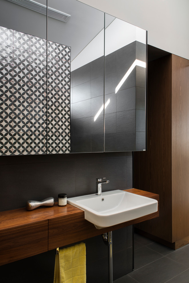 Design ideas for a mid-sized contemporary master bathroom in Sydney with an integrated sink, flat-panel cabinets, medium wood cabinets, wood benchtops, an alcove shower, a one-piece toilet, gray tile, ceramic tile, grey walls and porcelain floors.