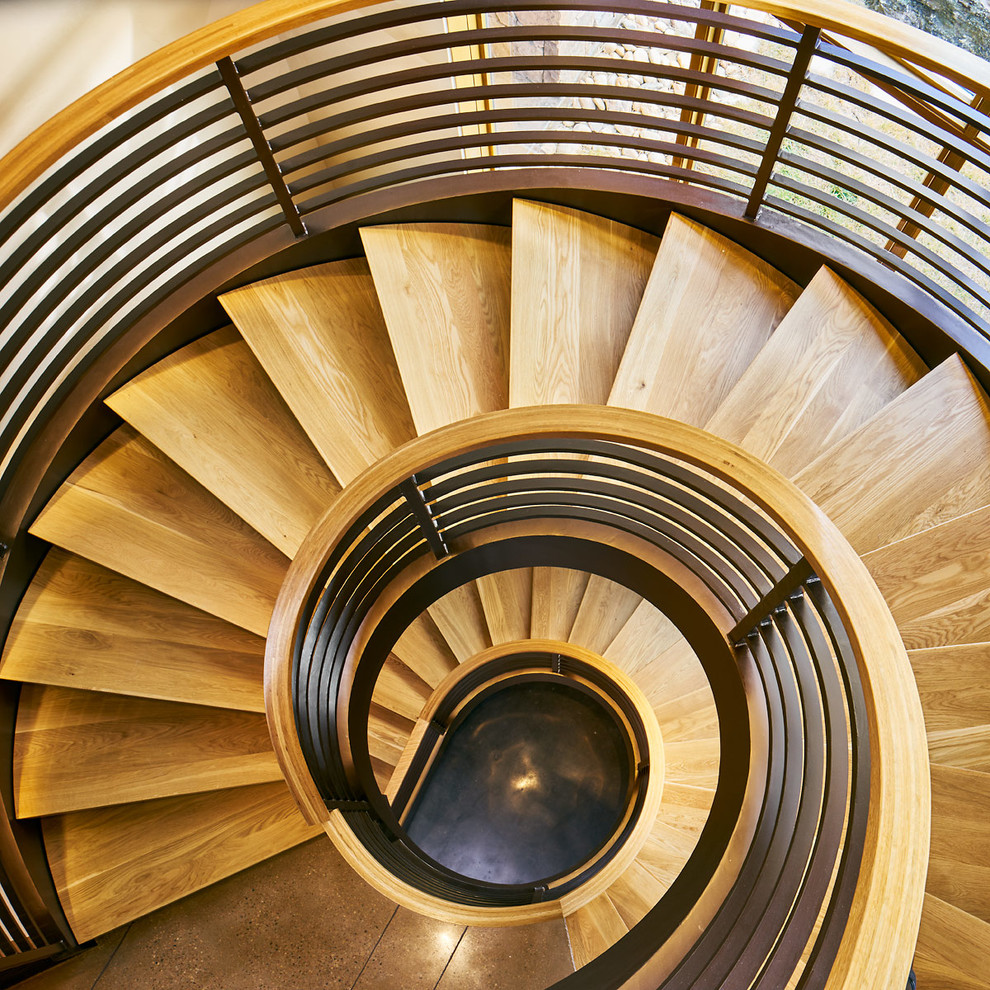 Large mountain style wooden curved light wood floor and metal railing staircase photo in Denver with beige walls and wooden risers