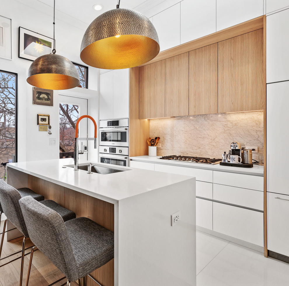 This is an example of a small contemporary single-wall open plan kitchen in Chicago with an undermount sink, flat-panel cabinets, quartz benchtops, panelled appliances, light hardwood floors, with island and white benchtop.