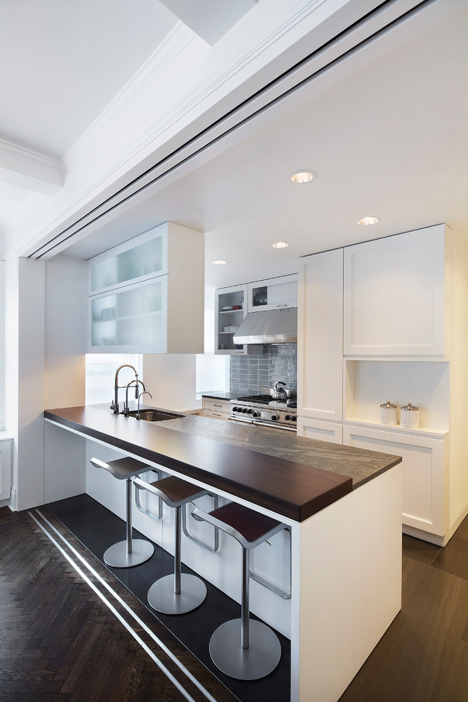 Mid-sized modern galley eat-in kitchen in New York with a single-bowl sink, shaker cabinets, white cabinets, wood benchtops, blue splashback, ceramic splashback, stainless steel appliances and a peninsula.
