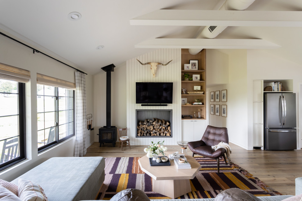 Imagen de salón para visitas machihembrado, abierto y abovedado actual pequeño con paredes blancas, suelo de madera clara, estufa de leña y televisor colgado en la pared