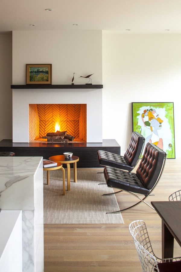 Photo of a midcentury open concept living room in DC Metro with light hardwood floors, a standard fireplace, a brick fireplace surround and white walls.