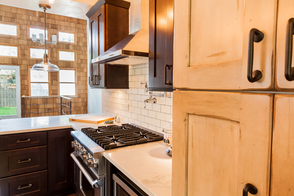 This is an example of a mid-sized industrial galley eat-in kitchen in Chicago with a farmhouse sink, shaker cabinets, dark wood cabinets, quartzite benchtops, white splashback, ceramic splashback, stainless steel appliances, dark hardwood floors and a peninsula.