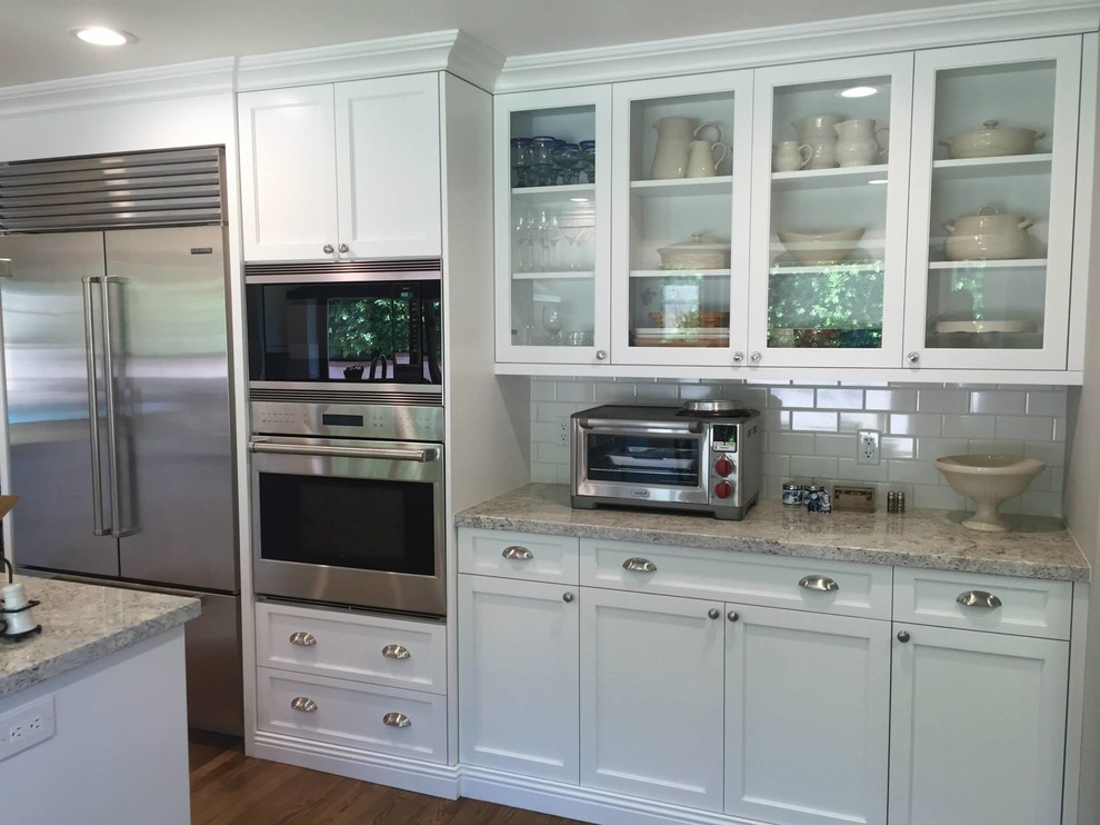 Kitchen - large transitional medium tone wood floor kitchen idea in Phoenix with an undermount sink, shaker cabinets, white cabinets, granite countertops, white backsplash, subway tile backsplash, stainless steel appliances and an island