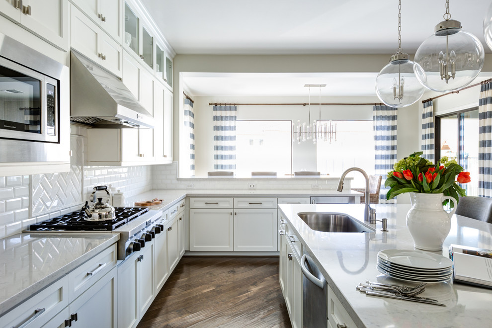 Open concept kitchen - large transitional l-shaped medium tone wood floor open concept kitchen idea in Phoenix with shaker cabinets, white cabinets, quartz countertops, white backsplash, subway tile backsplash, stainless steel appliances, an island and an undermount sink