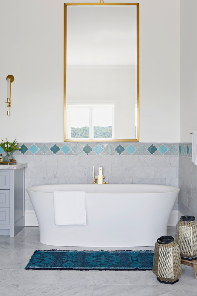 Photo of a large transitional master bathroom in Nashville with a freestanding tub, an open shower, a one-piece toilet, blue tile, marble, white walls, marble floors, an undermount sink, marble benchtops, white floor, a hinged shower door and white benchtops.