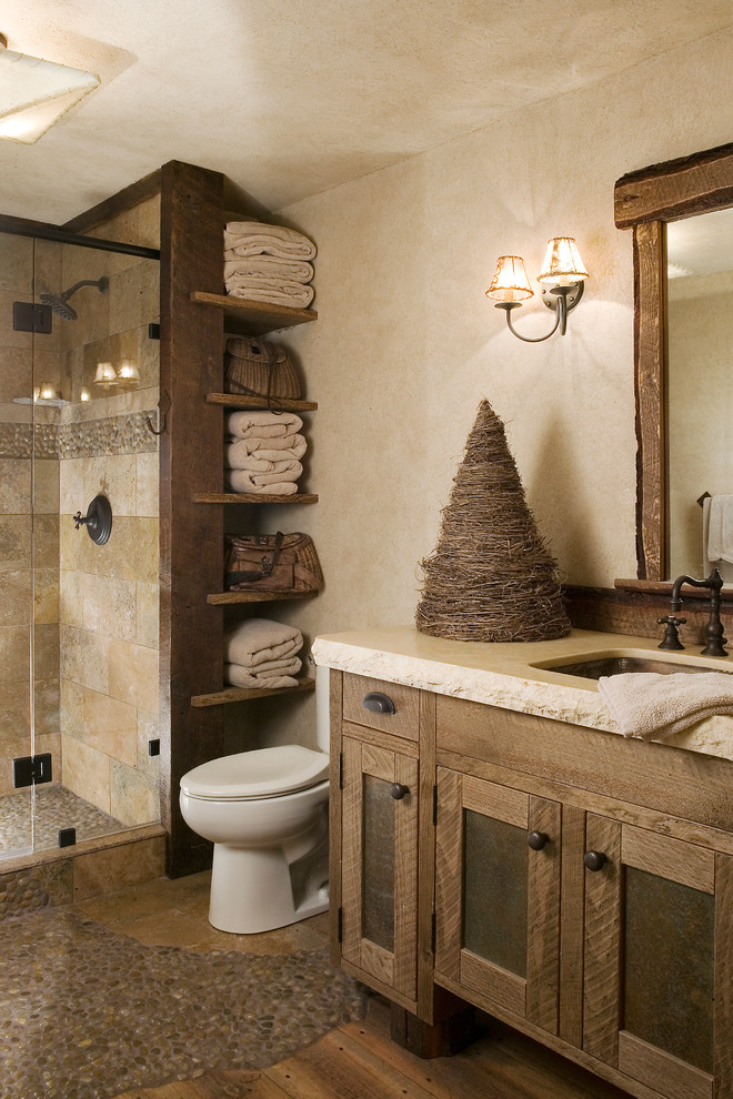 Country bathroom in Sacramento with an undermount sink, shaker cabinets, medium wood cabinets, an alcove shower, a two-piece toilet, beige tile, beige walls, pebble tile floors, travertine and white benchtops.