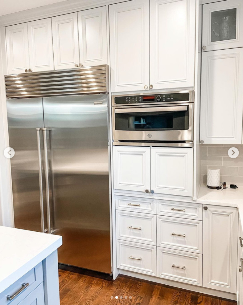 Large country l-shaped eat-in kitchen in Seattle with an undermount sink, recessed-panel cabinets, white cabinets, marble benchtops, white splashback, ceramic splashback, stainless steel appliances, medium hardwood floors, with island, brown floor and white benchtop.