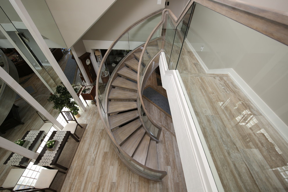 This is an example of a large modern wood curved staircase in Orange County with open risers.