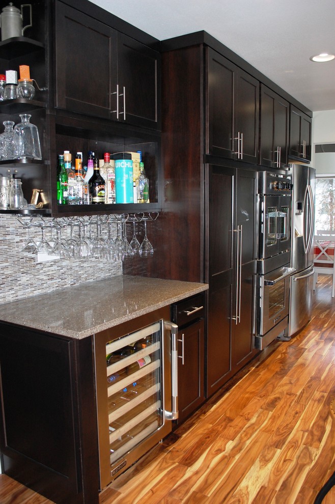 Inspiration for a mid-sized transitional l-shaped light wood floor and brown floor eat-in kitchen remodel with shaker cabinets, dark wood cabinets, an undermount sink, quartz countertops, glass tile backsplash, stainless steel appliances, metallic backsplash and an island