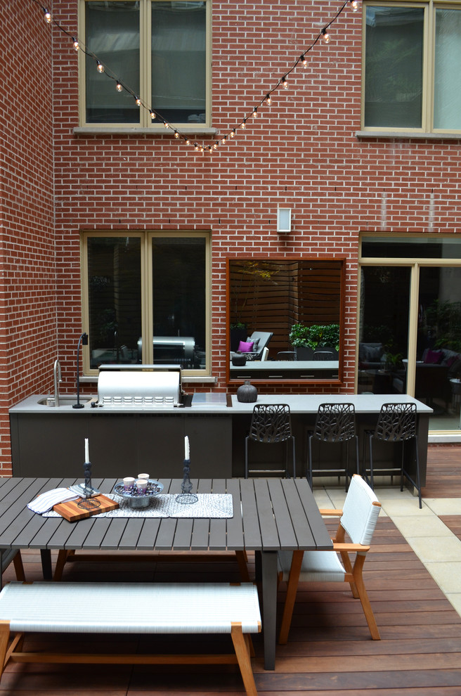 This is an example of a mid-sized contemporary courtyard patio in New York with an outdoor kitchen, decking and no cover.