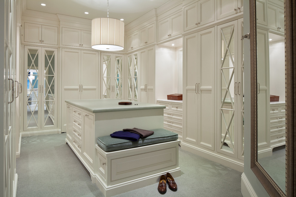 This is an example of a traditional women's dressing room in Columbus with glass-front cabinets, white cabinets and carpet.
