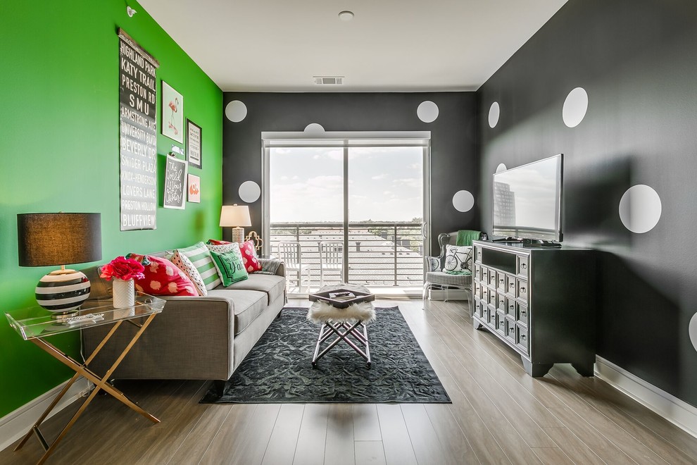 This is an example of a contemporary living room in Dallas with green walls, medium hardwood floors, a freestanding tv and brown floor.