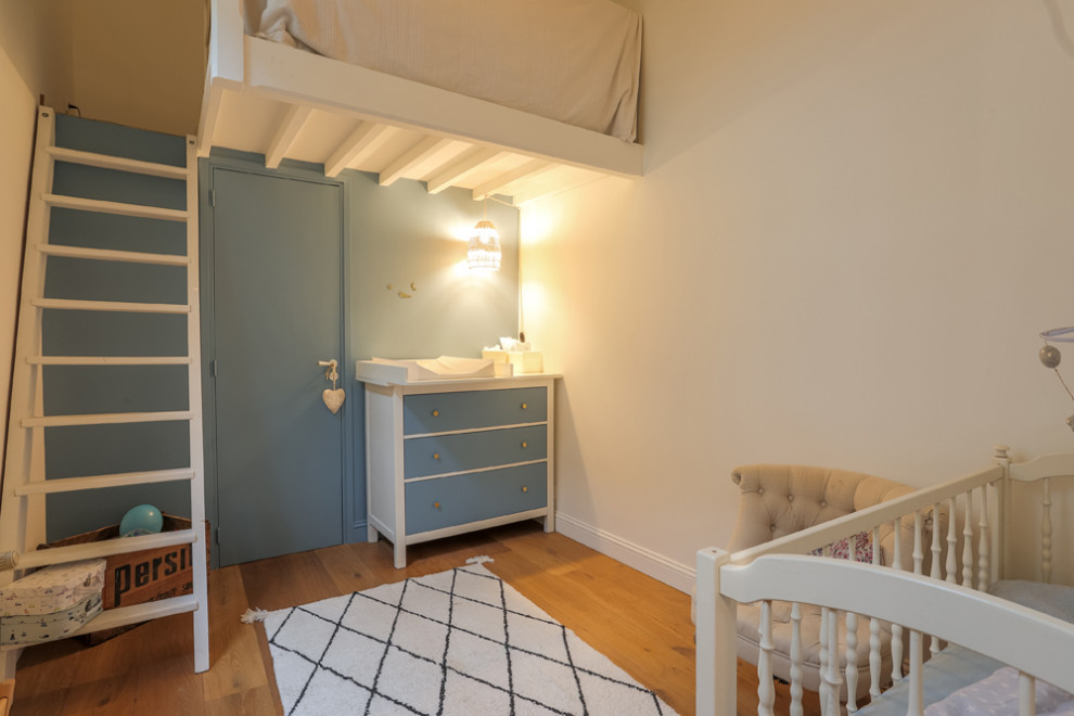 Inspiration for a mid-sized traditional nursery for boys in Paris with multi-coloured walls, light hardwood floors and beige floor.