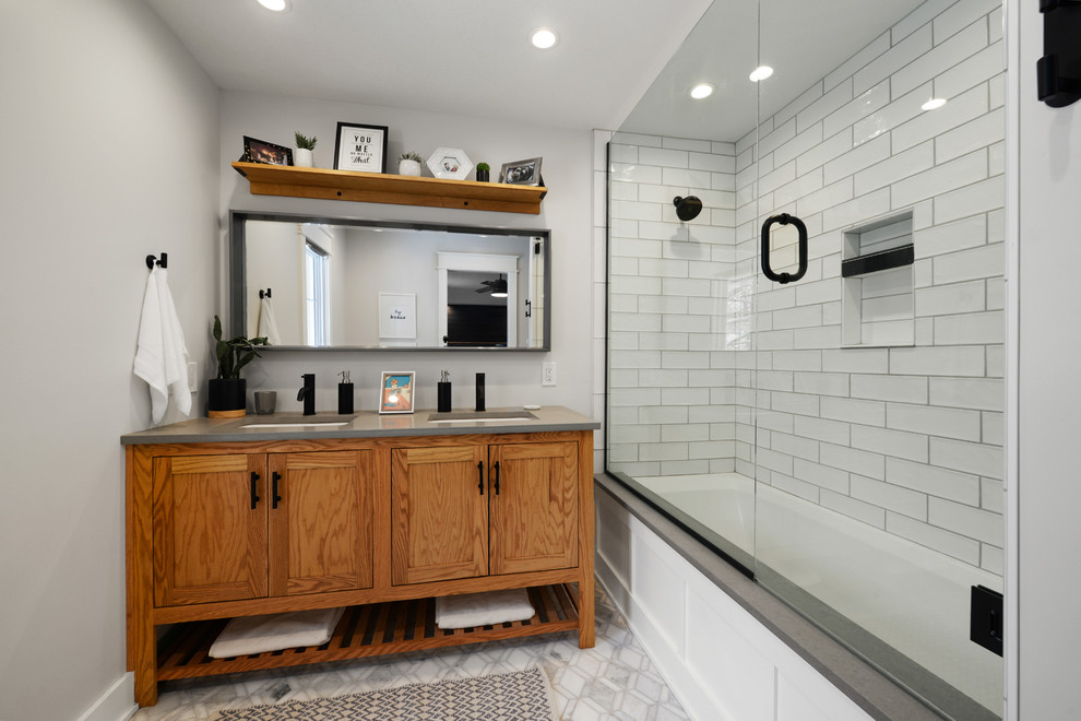 This is an example of a small traditional master bathroom in Kansas City with recessed-panel cabinets, medium wood cabinets, an alcove tub, a shower/bathtub combo, white tile, ceramic tile, white walls, ceramic floors, grey floor, a sliding shower screen and grey benchtops.