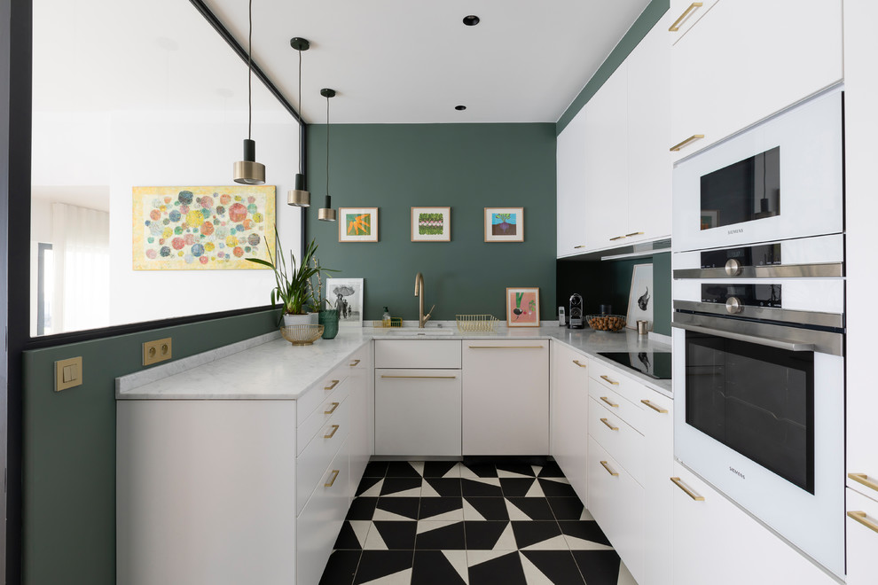 This is an example of a mid-sized contemporary u-shaped kitchen in Paris with a single-bowl sink, white cabinets, green splashback, white appliances, porcelain floors, black floor and white benchtop.