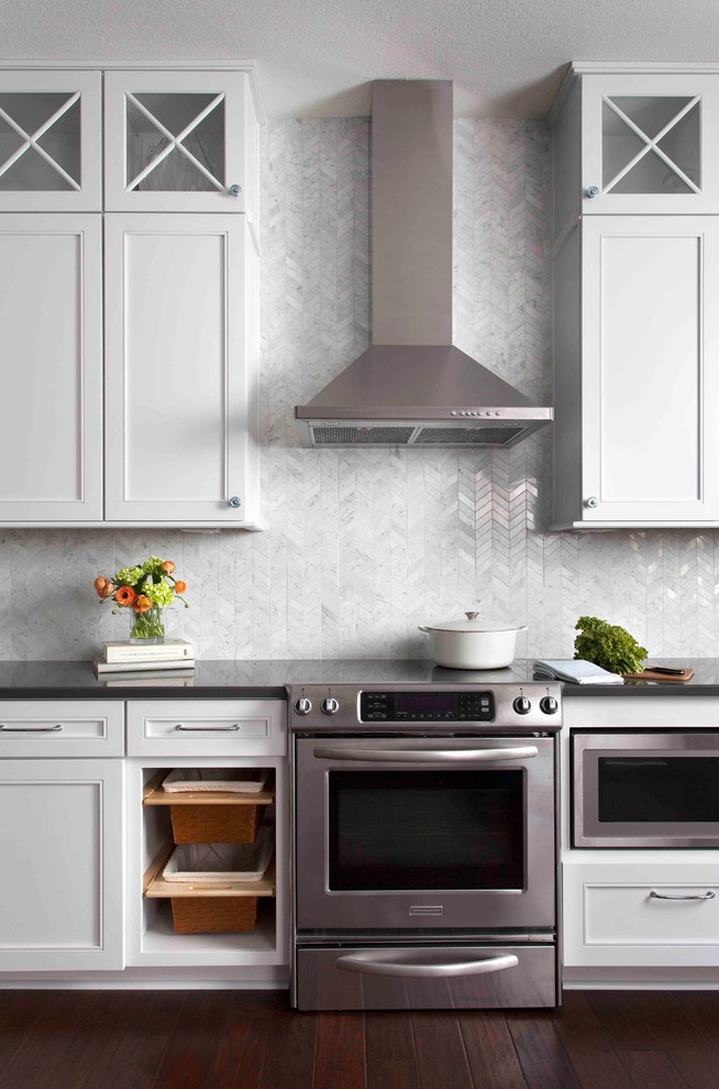 Inspiration for a large transitional dark wood floor and brown floor eat-in kitchen remodel in Austin with white cabinets, stone tile backsplash, stainless steel appliances, shaker cabinets, solid surface countertops, white backsplash, black countertops and an island