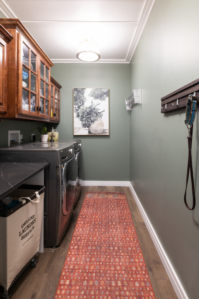 Idéer för små vintage svart tvättstugor, med luckor med upphöjd panel, skåp i mellenmörkt trä, bänkskiva i kvarts, gröna väggar, vinylgolv, en tvättmaskin och torktumlare bredvid varandra och brunt golv
