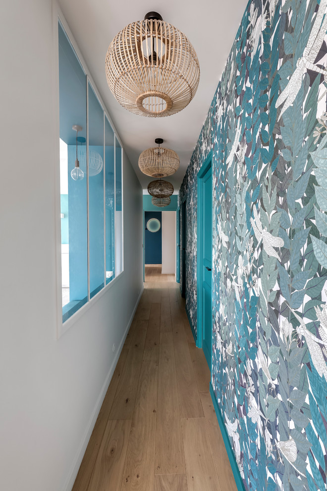 Photo of a contemporary hallway in Paris with blue walls, light hardwood floors and brown floor.