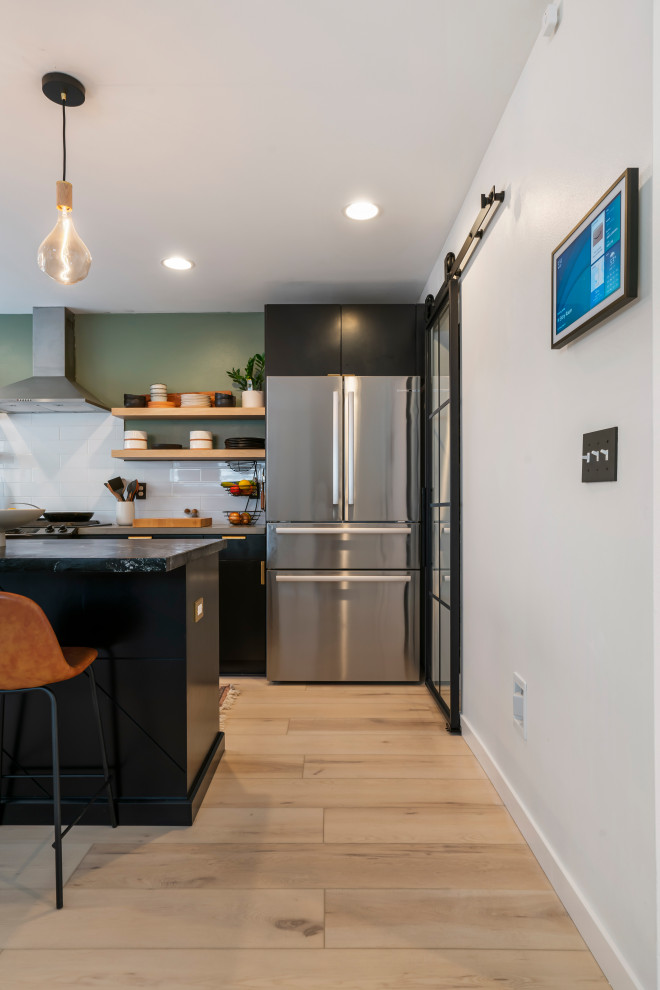 Large midcentury l-shaped eat-in kitchen in Seattle with a drop-in sink, flat-panel cabinets, black cabinets, marble benchtops, white splashback, ceramic splashback, stainless steel appliances, vinyl floors, with island, beige floor and grey benchtop.