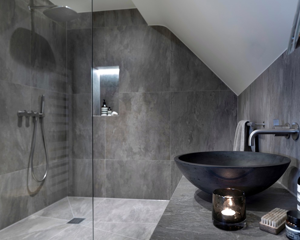 Small contemporary 3/4 wet room bathroom in Cheshire with open cabinets, a wall-mount toilet, gray tile, porcelain tile, grey walls, porcelain floors, a trough sink, tile benchtops, grey floor, an open shower and grey benchtops.